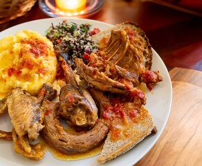 Traditional rustic Brazilian food, guinea fowl, Numida meleagris, with polenta, artisanal bread, and quinoa tabbouleh with vegetables. Real food