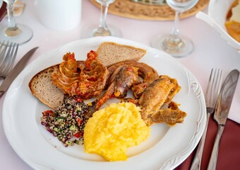 Traditional rustic Brazilian food, guinea fowl, Numida meleagris, with polenta, artisanal bread, and quinoa tabbouleh with vegetables. Real food