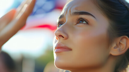 Close up of a woman looking up with the american flag in the background with a hand saluting it