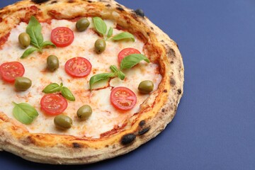 Delicious pizza with tomatoes, basil and olives on blue background, closeup. Space for text