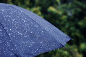 Blue umbrella under heavy rain outdoors, closeup