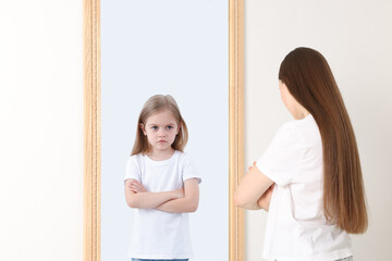 Young woman seeing herself as child in mirror. Conceptual collage about past and future, flow of...