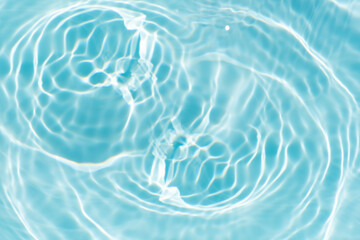 Blue water with ripples on the surface. Defocus blurred transparent blue colored clear calm water surface texture with splashes and bubbles. Water waves with shining pattern texture background.