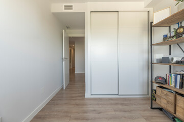 Master bedroom with a double wardrobe in light wood and large mirrors for a bright atmosphere
