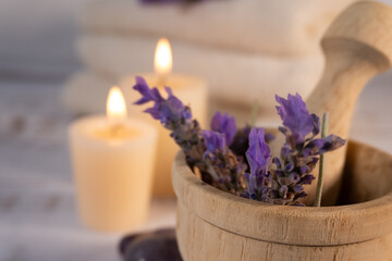Close-up of lavender flowers in a mortar with candles and spa towels in the background