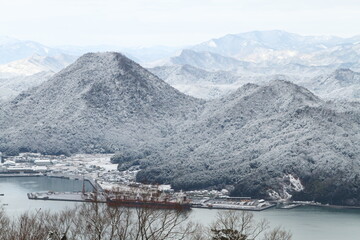 雪の残る山と港