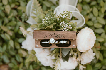 wedding rings in wooden box on top of bouquet