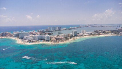 A beautiful blue ocean with a small island in the middle. The island is surrounded by a few buildings and a few boats. Aerial Views of Cancun Hotel zone, Quintana Roo Mexico 