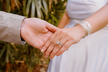 bride and groom holding hands with wedding ring