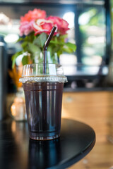 Iced black coffee in plastic cup on table at coffee shop.