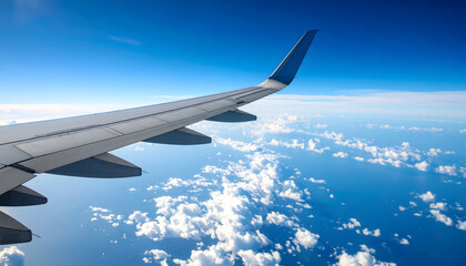 Fototapeta premium Airplane Wing Against Blue Sky with Fluffy Clouds during Flight