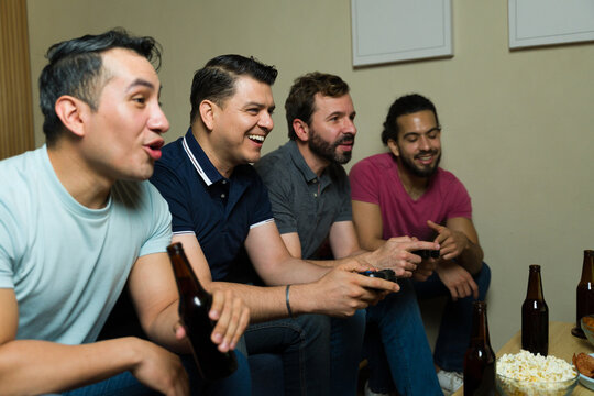 Group of friends playing video games and drinking beer at home