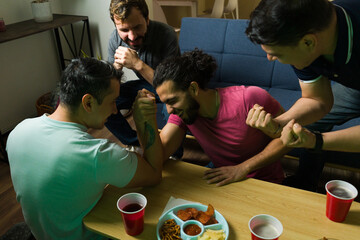 Group of friends arm wrestling and having fun at home