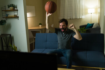 Excited basketball fan celebrating goal watching tv at home