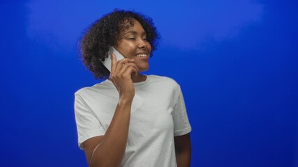 Woman naturally smiling and holding smartphone to ear in studio; positive conversation connection optimism.