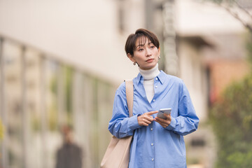 スマートフォンを持ち街中を歩く女性。