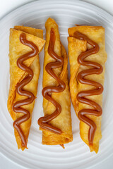 Gourmet dessert of sweet flautas or crispy pastry rolls drizzled with Arequipe (Dulce de Leche), a...