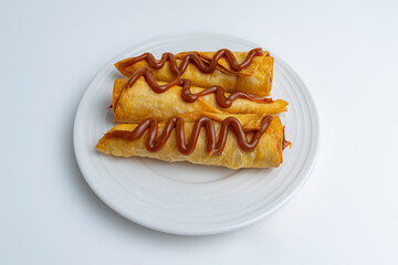 Gourmet dessert of sweet flautas or crispy pastry rolls drizzled with Arequipe (Dulce de Leche), a...