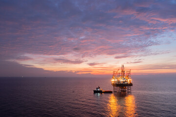 Fototapeta premium Areal view of offshore jack up rig and offshore platform during sunset for oil and gas exploration and production.