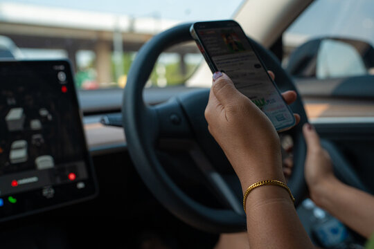 Woman hand use smartphone GPS navigator while drive EV car in city