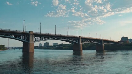Majestic concrete bridge spans a wide river under a cloudy sky