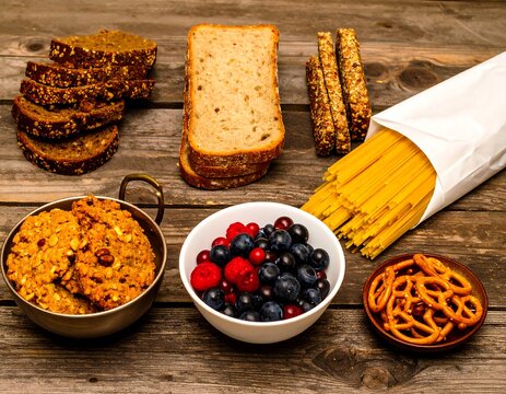 Assorted baked goods, pasta, and berries arranged on a rustic wooden surface - Powered by Adobe