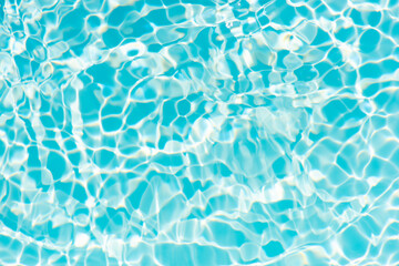 Blue water with ripples on the surface. Defocus blurred transparent blue colored clear calm water surface texture with splashes and bubbles. Water waves with shining pattern texture background.
