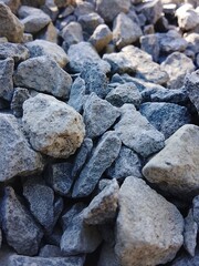A detailed close-up photo of rough gray stones, showcasing their natural texture, sharp edges, and rugged surface, often used in construction and landscaping.