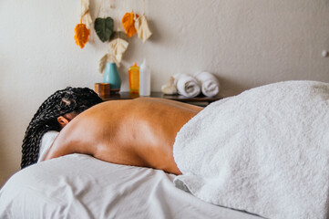 A woman is laying on a massage table with a towel draped over her back