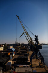 Large Gantry Crane at Industrial Waterfront with City Skyline. A striking yellow crane stands tall...