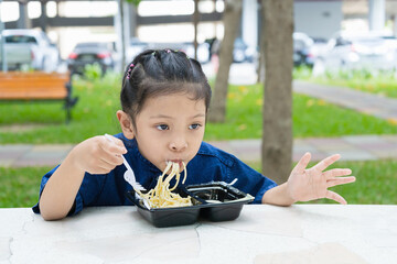 Girls eat spaghetti in the park.