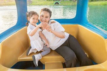 The mother of the Asian daughter is taking pictures on a floating boat.