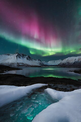 Aurora Borealis with Green and Pink Lights Over Snowy Mountains