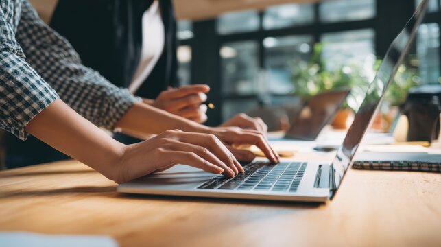 Hands Typing on Laptop in Modern Office Environment at Desk Setting