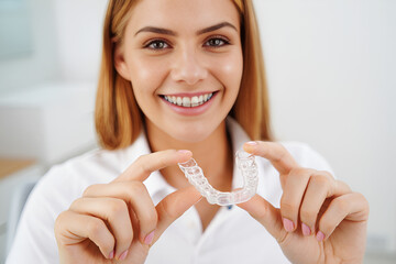 Woman holding clear dental aligners with a bright smile image