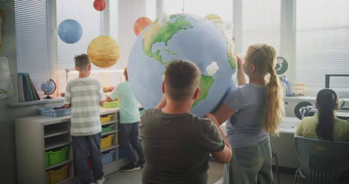 Ecology STEM Class: Elementary School Students Attaching Miniature Models of Clouds to Globe. Smart Kids Studying Science and Renewable Energy Resources Using Earth Planet Model in Modern Classroom.