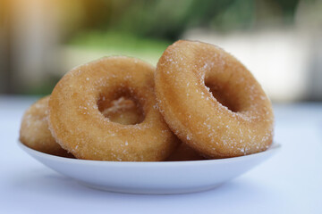 Homemade sugar milk donuts on white plate, soft and fluffy texture, buttery aroma, non-greasy fried snack. Delicious treat for eating or selling, concept of fried pastry and sweet dessert.         