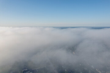 Aerial photo above the fog or white clouds with shining sun. Beautiful sunrise cloudy sky from aerial view. Above clouds from airplane window or drone.