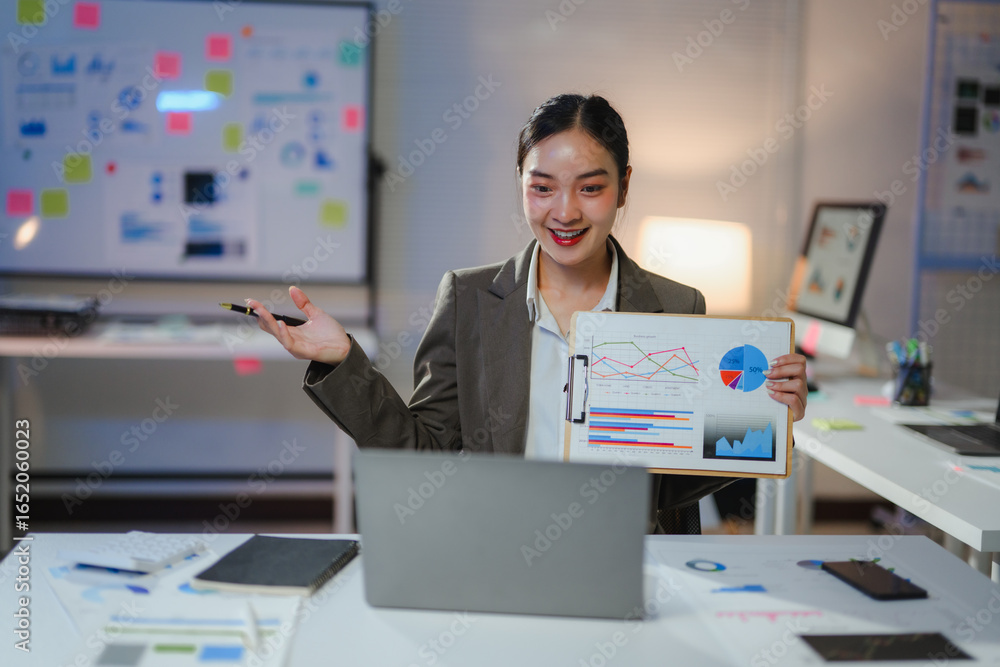 Poster young professional engaging in a presentation of financial data while using a laptop in a sleek, mod