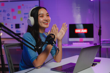 Energetic podcaster clapping hands while recording radio show in neon-lit home studio, expressing excitement and engagement