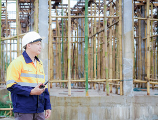 Construction workers wearing hard hats and reflective vests are working on a construction site and...