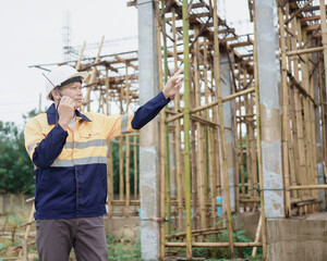 Construction workers wearing hard hats and reflective vests are working on a construction site and...