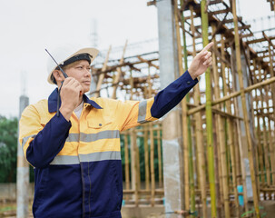 Construction workers wearing hard hats and reflective vests are working on a construction site and...