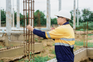 Construction workers wearing hard hats and reflective vests are working on a construction site and...