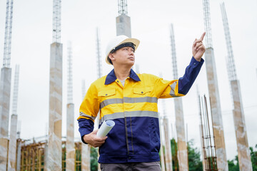 Construction workers wearing hard hats and reflective vests are working on a construction site and...