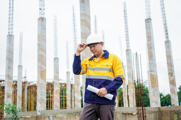 Construction workers wearing hard hats and reflective vests are working on a construction site and...