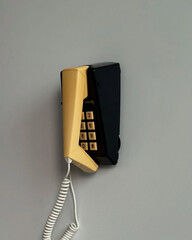 Yellow wall-mounted telephone with visible numeric keypad.