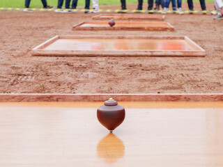 Traditional wooden spinning top standing on smooth surface with blurred background, symbol of...