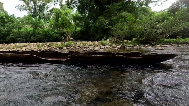 An old an broken wooden canoe has been left in a tropical stream; nature background