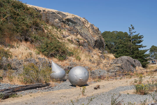 A pair of decommissioned metal naval mines displayed outdoors on rocky ground at Fort Rodd Hill, Victoria, Vancouver Island, Canada.